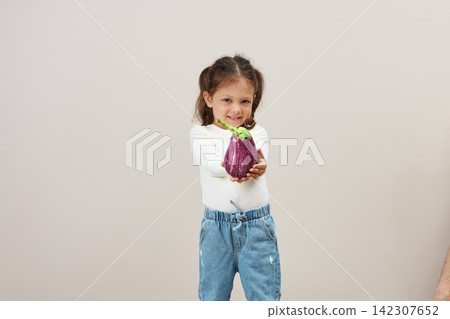 Little girl presenting fresh striped eggplant for healthy eating Little girl presenting fresh striped eggplant for healthy eating 142307652