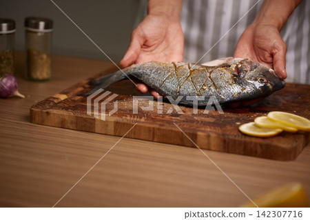 Chef preparing fresh gilt-head bream for cooking Chef preparing fresh gilt-head bream for cooking 142307716