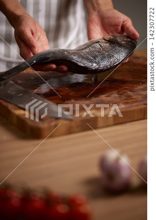 Chef hands holding fresh raw fish ready for cooking 142307722