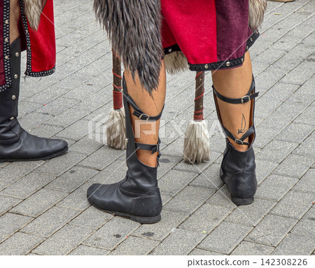 Participant displays legs in black leather boots with buckles and a sailboat tattoo on a paved street Participant displays legs in black leather boots with buckles and a sailboat tattoo on a paved street 142308226