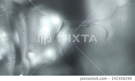 Water droplets and condensation on a steamy glass creating abstract wet texture background with soft bokeh lights 142308299