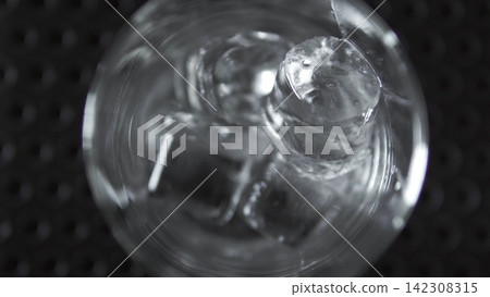 Glass of water with melting ice cubes, overhead view, refreshing cold drink, abstract texture and liquid motion Glass of water with melting ice cubes, overhead view, refreshing cold drink, abstract texture and liquid motion 142308315