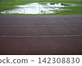 Athletics track after heavy rain with flooded grass, making outdoor training difficult in autumn 142308830
