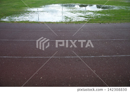 Athletics track after heavy rain with flooded grass, making outdoor training difficult in autumn Athletics track after heavy rain with flooded grass, making outdoor training difficult in autumn 142308830