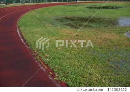 Athletics track after heavy rain with flooded grass, making outdoor training difficult in autumn 142308832