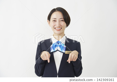 一位中年女員工在白色背景前向下指著。 142309161