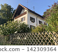 Traditional white Bavarian house behind a wooden fence 142309364