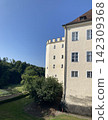 White medieval castle tower and grassy ditch slope 142309368