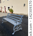 Empty white wooden bench near an old stone wall 142309370