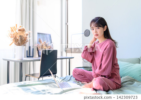 一名女子在床上使用筆記型電腦。 一名女子在床上使用筆記型電腦。 142309723