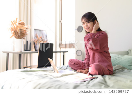 A woman touching her hair while using a laptop. 142309727