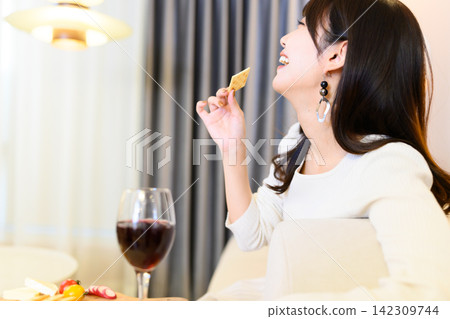 A woman eating a cracker, a wine glass A woman eating a cracker, a wine glass 142309744