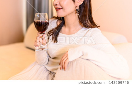 身穿白色毛衣的女子,手拿酒杯。 身穿白色毛衣的女子,手拿酒杯。 142309746