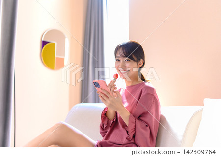 A woman holding a smartphone and a cherry tomato. A woman holding a smartphone and a cherry tomato. 142309764