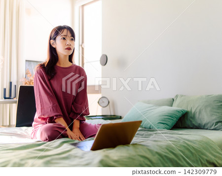 Woman looking at laptop in bed Woman looking at laptop in bed 142309779