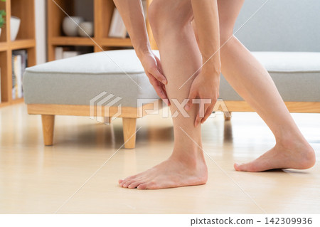 A young man removes hair from his legs at home. A young man removes hair from his legs at home. 142309936