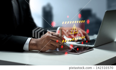 Businessman working on a laptop and tablet with a holographic virus alert and malware warning hologram floating above. Concept of Technology Security 142310370
