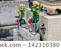 Colorful flowers and a metal vase placed on the tombstone 142310380