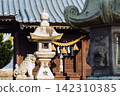 Stone lanterns and guardian lion-dogs line the grounds of a Japanese shrine. 142310385