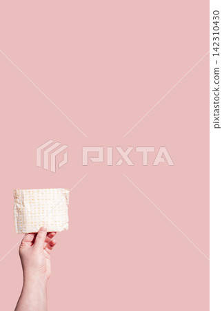 Classic menstrual pads in woman hand. Menstrual cycle and suffering from menstrual pain. Female period and intimate hygiene Classic menstrual pads in woman hand. Menstrual cycle and suffering from menstrual pain. Female period and intimate hygiene 142310430