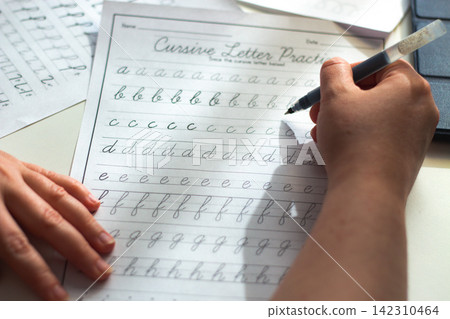 Person seated at desk deeply focused on writing in notebook. Physical engagement of motor skills Handwriting as brain training. Prevention of age related cognitive decline. Senior or adult practicing Person seated at desk deeply focused on writing in notebook. Physical engagement of motor skills Handwriting as brain training. Prevention of age related cognitive decline. Senior or adult practicing 142310464