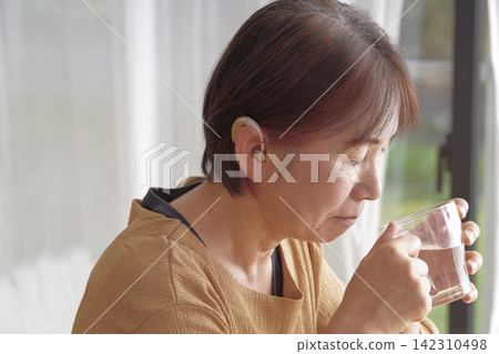 Senior women using behind-the-ear hearing aids Senior women using behind-the-ear hearing aids 142310498