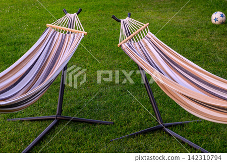 Two matching hammocks in a vibrant green lawn setting Two matching hammocks in a vibrant green lawn setting 142310794
