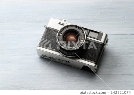 A vintage film camera placed on a wooden table. A vintage film camera placed on a wooden table. 142311074