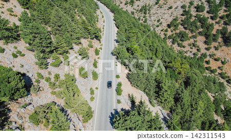 Aerial top down view of black car driving on asphalt road through dense green pine forest in mountains during sunny day horizontal stock photo Aerial top down view of black car driving on asphalt road through dense green pine forest in mountains during sunny day horizontal stock photo 142311543