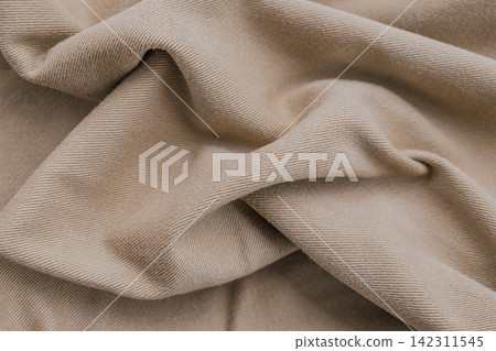 Close up top view of folded beige cotton twill fabric with soft shadow details forming abstract draped background horizontal stock photo Close up top view of folded beige cotton twill fabric with soft shadow details forming abstract draped background horizontal stock photo 142311545
