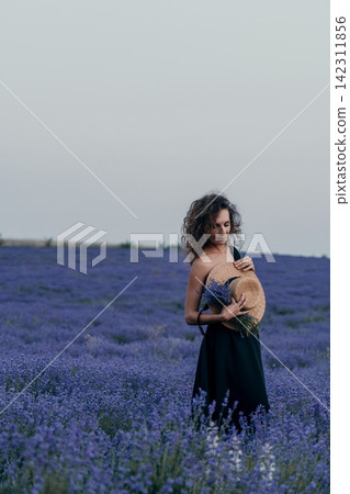 Woman lavender field straw hat holding purple flowers in a blooming meadow during a peaceful summer evening sunset stroll Woman lavender field straw hat holding purple flowers in a blooming meadow during a peaceful summer evening sunset stroll 142311856