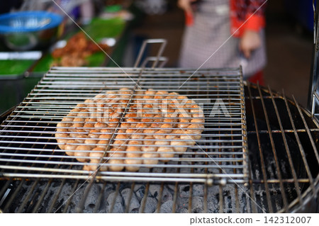 Grilled sausage arranged on metal barbecue rack at outdoor market Grilled sausage arranged on metal barbecue rack at outdoor market 142312007