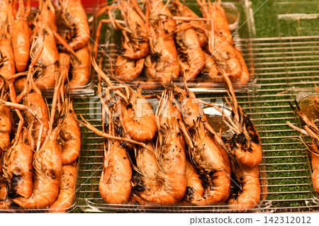 Grilled shrimp arranged on metal rack at outdoor food market Grilled shrimp arranged on metal rack at outdoor food market 142312012