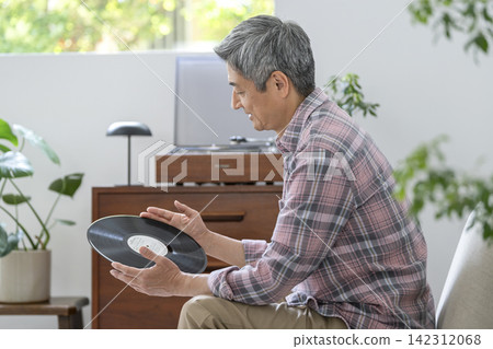 A man in his 60s holding a record A man in his 60s holding a record 142312068