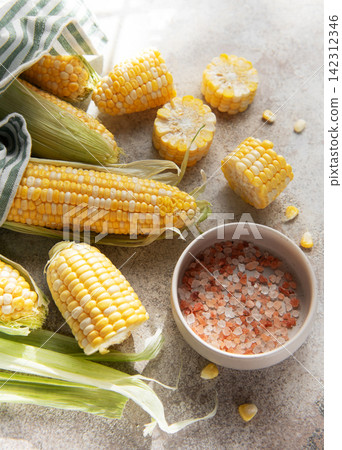 Fresh sweet corn cobs with salt on table Fresh sweet corn cobs with salt on table 142312346