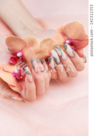 Woman's hands holding orchids with elegant nail art manicure Woman's hands holding orchids with elegant nail art manicure 142312353