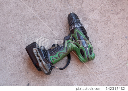 Cordless drill lying on concrete floor. Portable electric screwdriver tool for construction and repair work. Professional industrial equipment for renovation, building and diy project. Cordless drill lying on concrete floor. Portable electric screwdriver tool for construction and repair work. Professional industrial equipment for renovation, building and diy project. 142312482