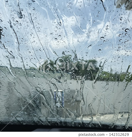 The windshield being rinsed with water during the rinsing process of an automatic car wash. The windshield being rinsed with water during the rinsing process of an automatic car wash. 142312629
