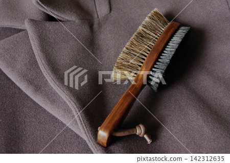 Image of caring for a favorite wool coat with a clothes brush. Image of caring for a favorite wool coat with a clothes brush. 142312635