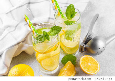 Refreshing homemade lemonade with lemon slices, fresh mint, ice and citrus juicer, cold beverage Refreshing homemade lemonade with lemon slices, fresh mint, ice and citrus juicer, cold beverage 142312853