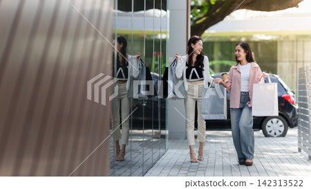 Happy Asian women walking together carrying shopping bags for retail consumer lifestyle Happy Asian women walking together carrying shopping bags for retail consumer lifestyle 142313522