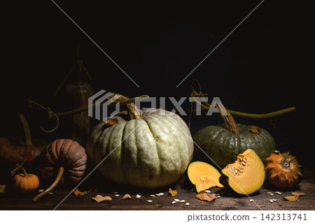 Assortment of pumpkins with cut pieces on wooden table Assortment of pumpkins with cut pieces on wooden table 142313741