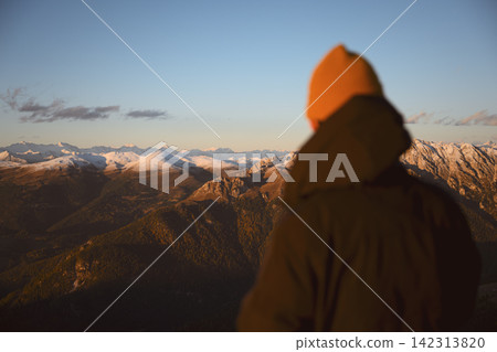 Person watching a colorful mountain sunset above the Dolomites Person watching a colorful mountain sunset above the Dolomites 142313820