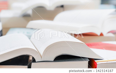 stack of books, close up. Open book on the table in library. Back to school concept. Open book on table with blur bookshelf background stack of books, close up. Open book on the table in library. Back to school concept. Open book on table with blur bookshelf background 142314187
