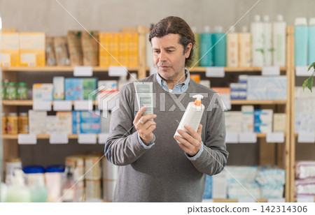 Male buyer chooses skin cream at drugstore 142314306