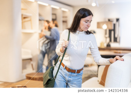 Woman looking at the upholstery on the sofa Woman looking at the upholstery on the sofa 142314336