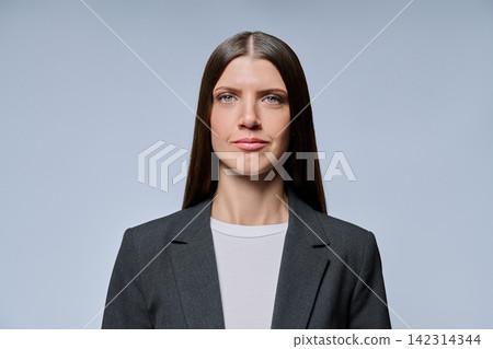 Serious businesswoman portrait looking at camera against grey background Serious businesswoman portrait looking at camera against grey background 142314344
