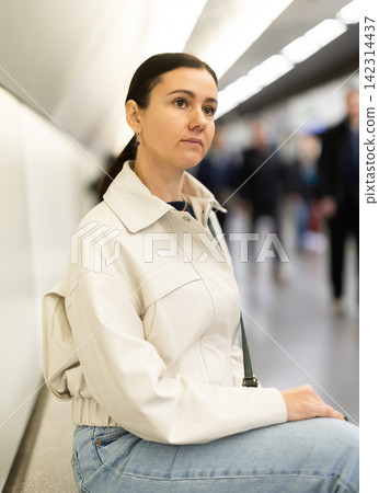 Girl is sitting on metro platform station, waiting for transport to arrive Girl is sitting on metro platform station, waiting for transport to arrive 142314437