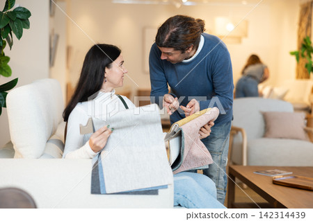 Husband discusses with his wife the purchase of upholstery for a sofa Husband discusses with his wife the purchase of upholstery for a sofa 142314439