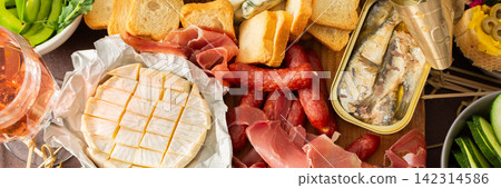 A colorful charcuterie board offers an inviting selection of cheeses, cured meats, fresh bread, nuts, and creamy hummus, perfect for sharing at a casual gathering or picnic, banner A colorful charcuterie board offers an inviting selection of cheeses, cured meats, fresh bread, nuts, and creamy hummus, perfect for sharing at a casual gathering or picnic, banner 142314586